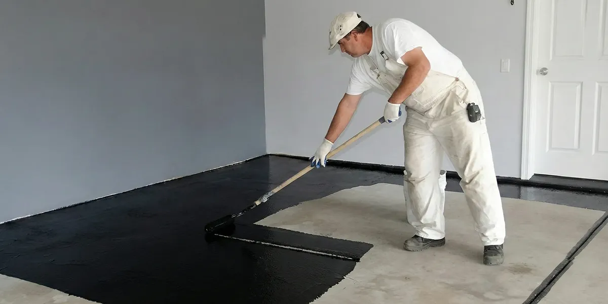 basement waterproofing professional applying waterproof coating to protect a basement floor in St Paul, MN